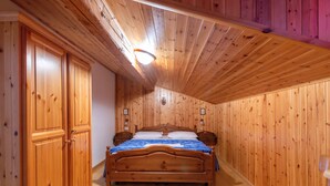 Une pièce aux murs lambrés, avec un lit, une armoire en bois et un luminaire au plafond.