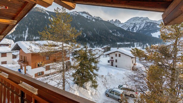 Une cabane en bois offrant une vue sur des maisons et des montagnes enneigées.