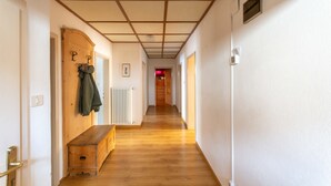 Un couloir doté d’un plancher en bois, d’un banc, d’un porte-manteau et d’un radiateur.