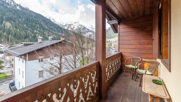 Un balcon en bois offrant une vue sur des montagnes enneigées et une ville située en contrebas.
