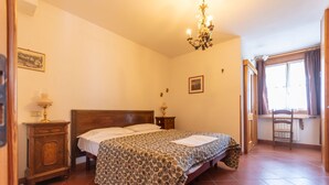 Une chambre à coucher avec un lit en bois, un lustre, une table de chevet, une commode et une fenêtre avec des rideaux.