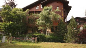 Un immeuble en bois à plusieurs étages, doté de balcons, entouré d’arbres et d’une zone herbeuse.