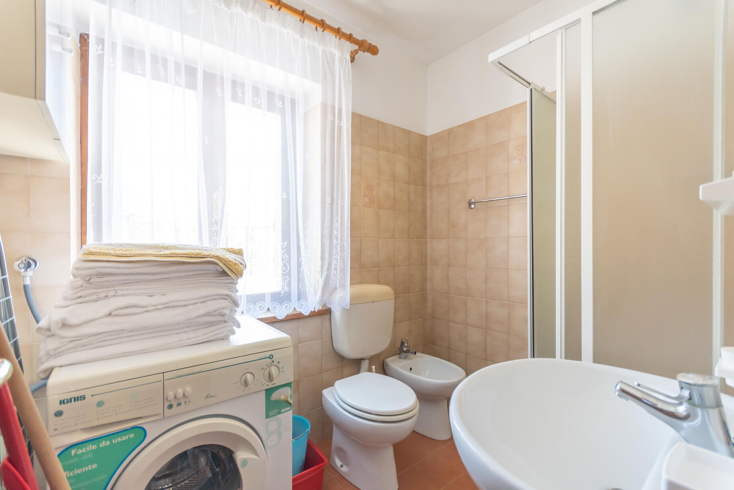 Une petite salle de bain équipée d’un lave-linge, de toilettes, d’un bidet et d’un lavabo.