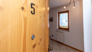 Une porte en bois portant le numéro 5, une fenêtre avec vue et un luminaire au plafond.