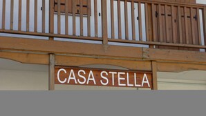 Et gelænder af træ på en balkon med et skilt, der står 'CASA STELLA'.