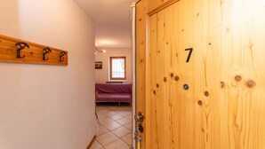 En trædør med nummer 7, en gang med en seng og et vindue, samt en vægmonteret hylde.