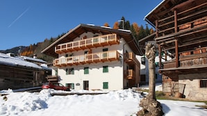 A traditional chalet-style building with a balcony, surrounded by snow. - Casa Lisa (Falcade)