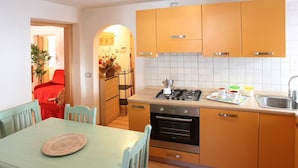 A compact kitchen with wooden cabinets, a gas stove, an oven, and a sink. - Casa Lisa (Falcade)