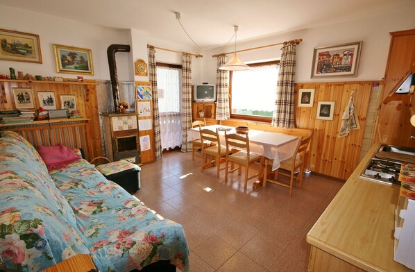 A cozy room with a bed, a dining table with chairs, a small kitchen area, and a fireplace.