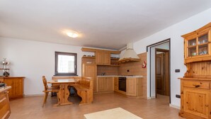 Une cuisine spacieuse avec des meubles de rangement en bois, une table à manger et un four encastré.