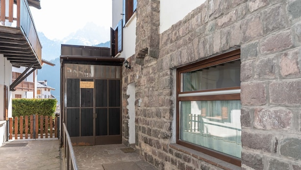 A stone building with a wooden balcony and a window overlooking a mountain.