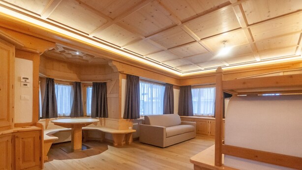 Ein gemütliches Interieur mit Holzboden, einem runden Tisch, einer Couch und einem Etagenbett.