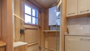 Eine kleine, kompakte Küche mit Holzausstattung, einem Fenster und einem eingebauten Kühlschrank.