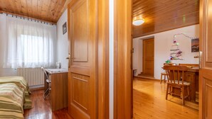 A wooden-paneled room with a bed, a desk, and a dining area. - Casa Morel (Falcade)