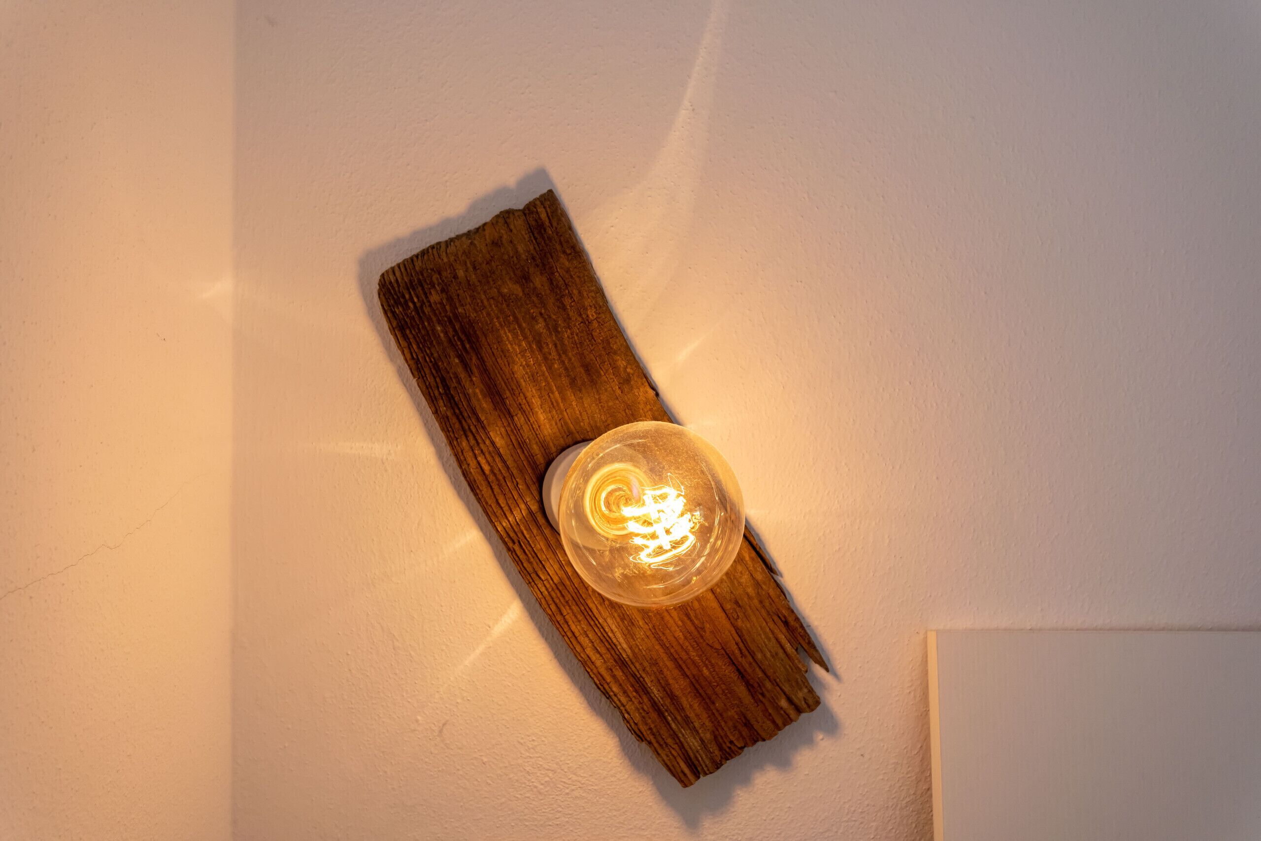 Una lámpara de pared con una bombilla de vidrio transparente y una base de madera.