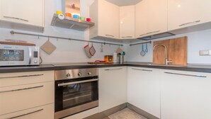 Uma cozinha moderna com armários brancos, forno embutido e cafeteira.