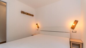 Quarto com cama, duas mesas de cabeceira e iluminação embutida na parede.