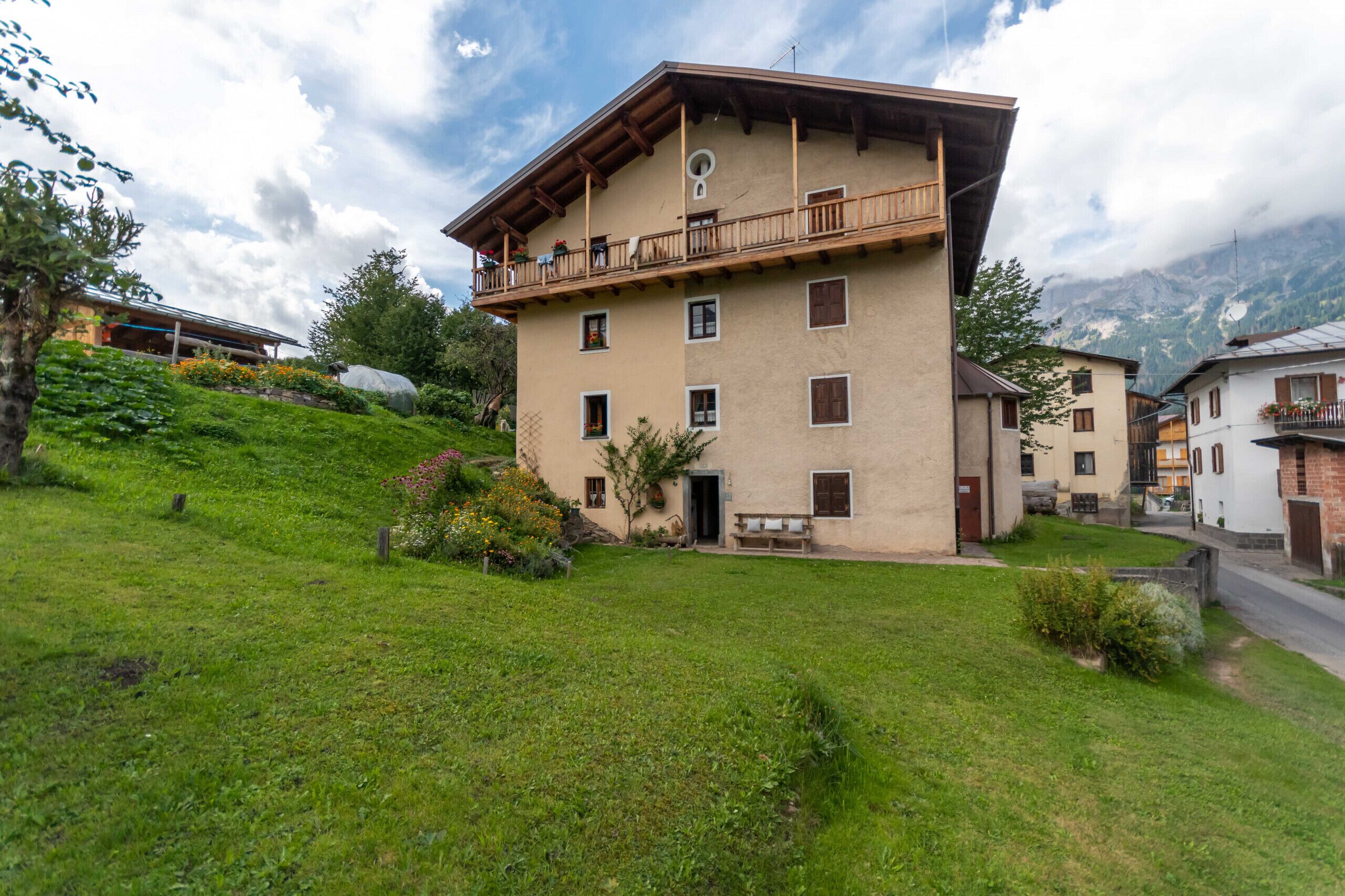 Ein mehrstöckiges Gebäude mit Balkon, umgeben von üppiger Vegetation und Bergen im Hintergrund.