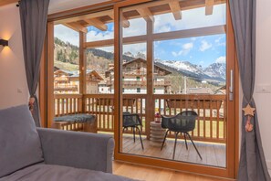 Una habitación con un amplio ventanal corredero que da a una terraza exterior con vistas a un paisaje montañoso.