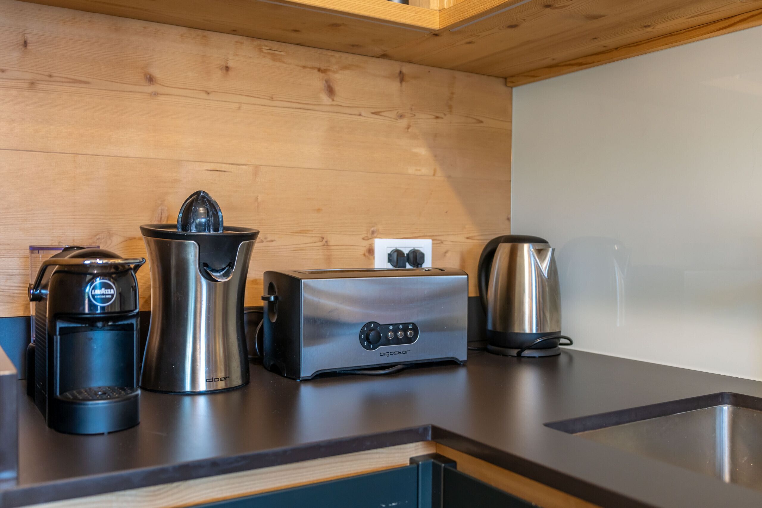 Ett kök med kaffebryggare, brödrost, vattenkokare och diskmaskin.