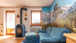 Ein gemütliches Wohnzimmer mit einem blauen Sofa, einem Kamin und einer Bergkulisse.