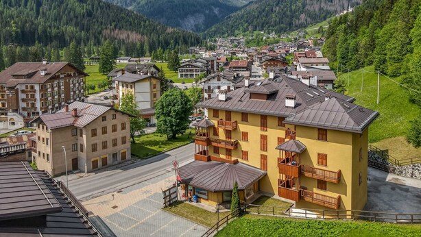 Eine Bergstadt mit traditioneller Architektur, einem zentralen Platz und Blick auf schneebedeckte Berge.