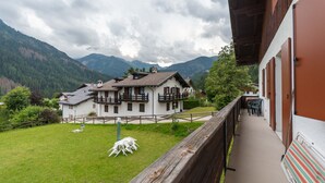 A chalet with a balcony overlooking a grassy yard and mountains. - Villa Elisena (Falcade)