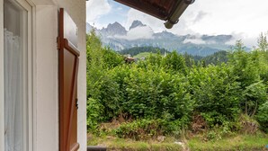 A view from a balcony with a wooden ceiling, overlooking a lush green landscape and distant mountains. - Villa Elisena (Falcade)
