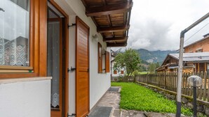 A wooden door, a stone pathway, and a view of mountains. - Casa Alice (Falcade)
