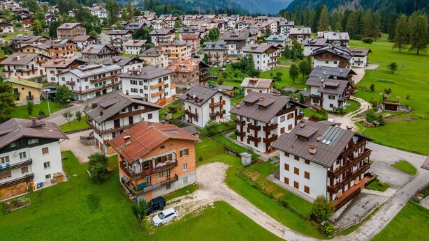 A residential area with houses, some with balconies, surrounded by green fields and mountains. - Casa Alice (Falcade)