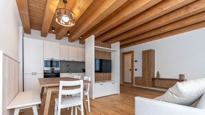 Eine moderne Küche mit weißen Schränken, einem Holztisch und einem integrierten Fernseher.