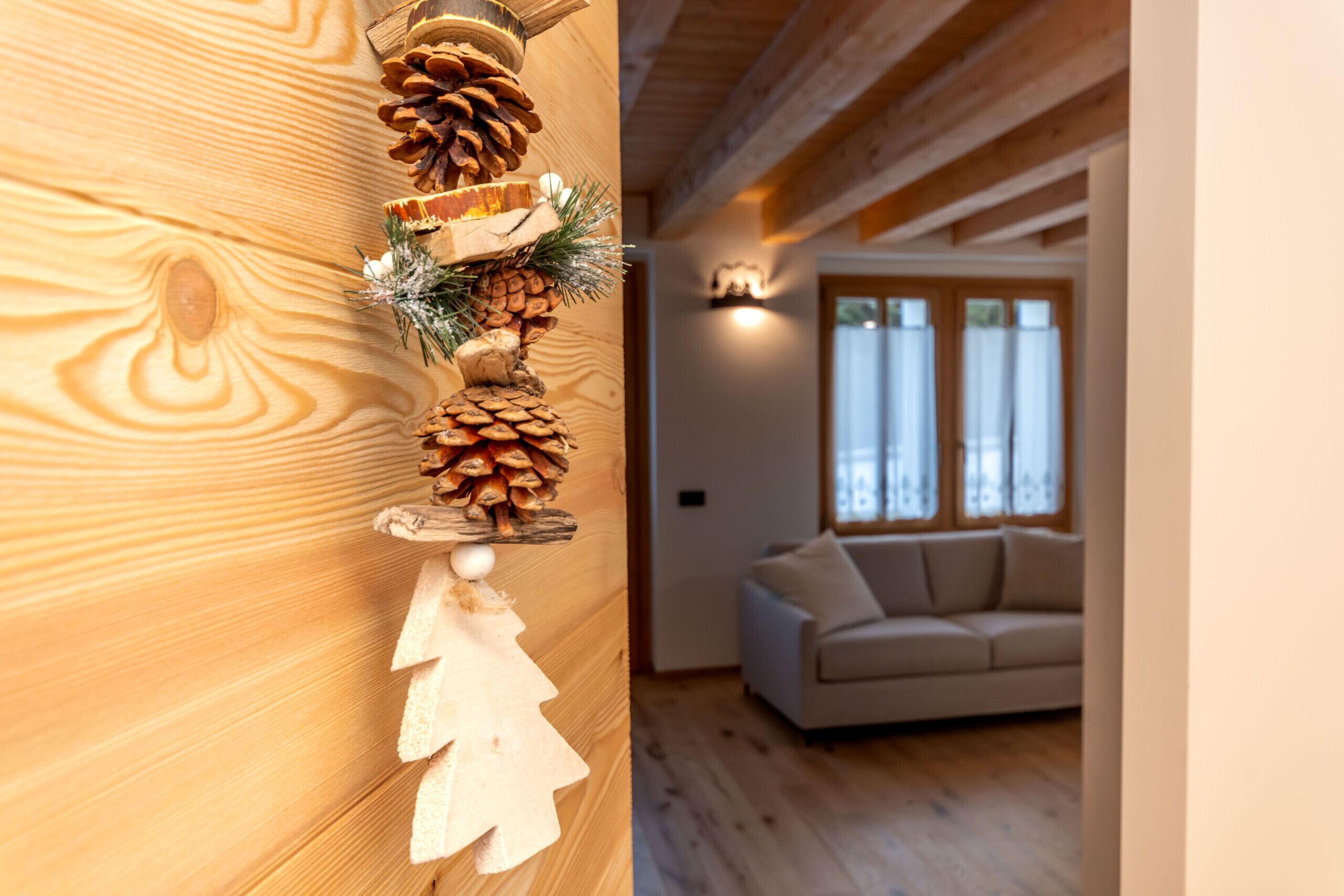 A wooden wall with a pine cone decoration and a white Christmas tree ornament.