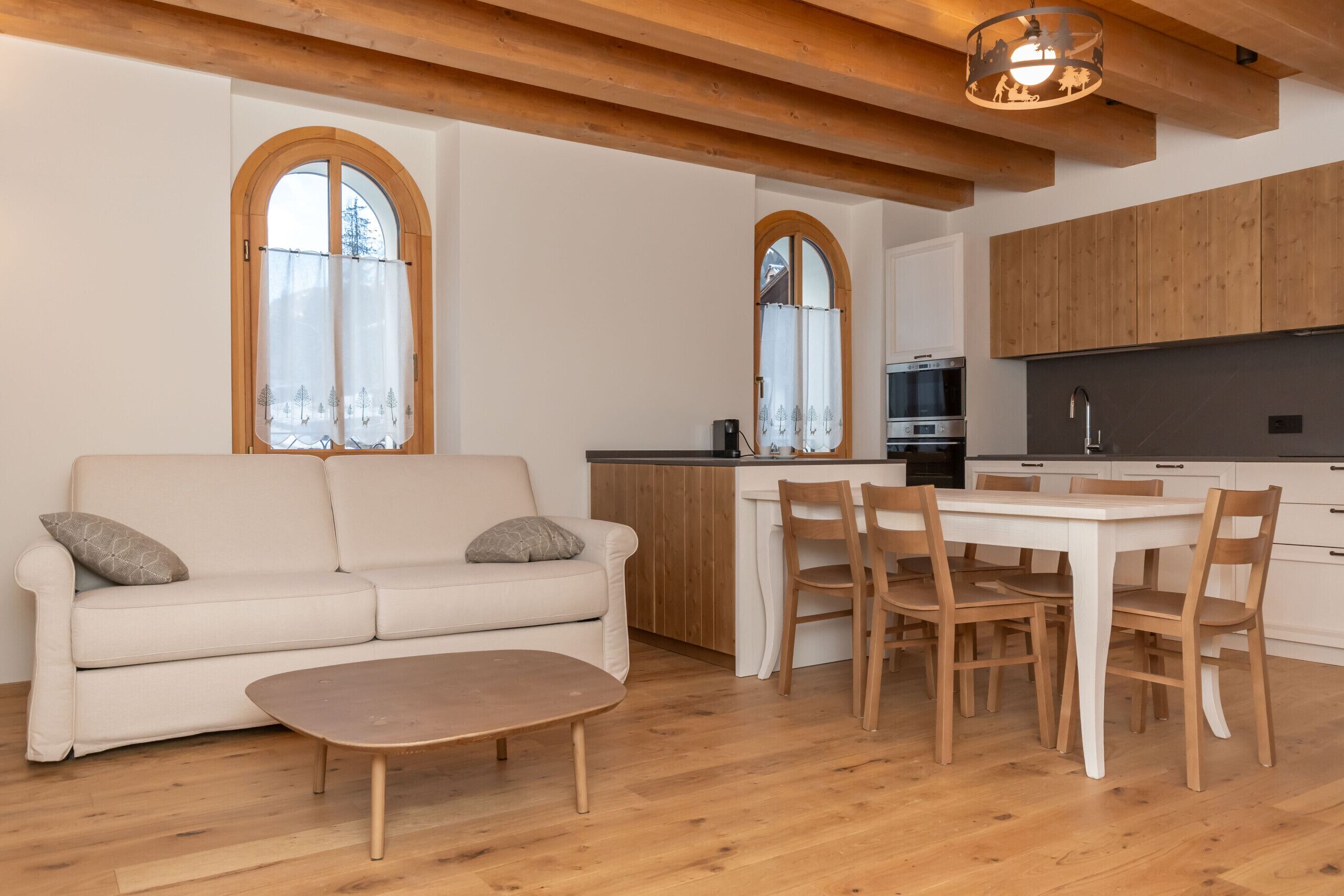 A modern kitchen with wooden cabinets, a dining table with chairs, and a sofa with a coffee table.
