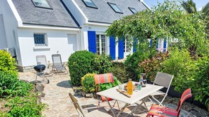 Une terrasse avec une table, des chaises et un espace barbecue.