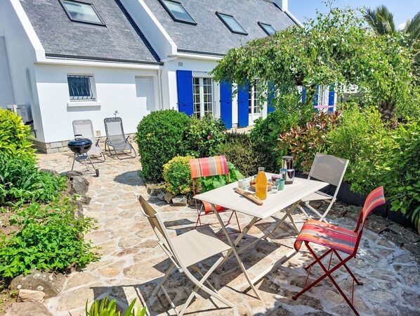 Eine Terrasse mit Tisch, Stühlen und Grillplatz.