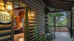 A cabin with a porch, green rocking chairs, and a welcome sign. - "Lil Cub" Cabin in Nebo Gated Community (Nebo)