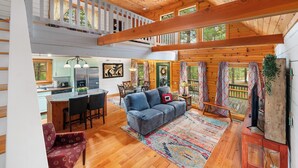 A spacious cabin interior with a large dining area, a cozy living room with a sofa and chairs, and a kitchen with modern appliances. - "Lil Cub" Cabin in Nebo Gated Community (Nebo)
