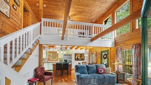 A spacious loft-style living area with a wooden staircase, a dining area, and a kitchen. - "Lil Cub" Cabin in Nebo Gated Community (Nebo)