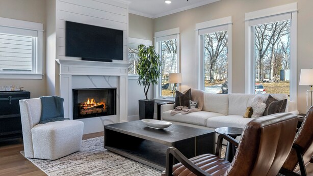 A living room with a fireplace, a sofa, a coffee table, and a TV mounted on the wall. - New luxurious home - hot tub, firepit, & trails - Walk or ride to downtown! (Bentonville)