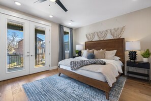 A bedroom with a bed, bedside tables, a ceiling fan, and a view through the door.