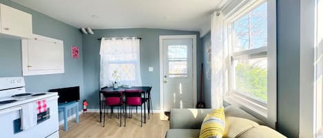 A compact living space with a kitchenette, dining area, and a sofa with cushions.