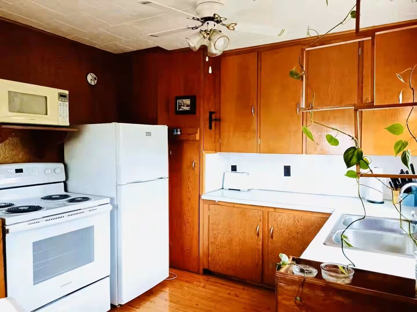 A compact kitchen with wooden cabinets, a white refrigerator, a stove, and a microwave.