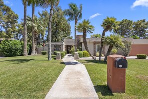 A residential area with a concrete pathway leading to a house with a mailbox.