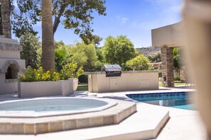 A backyard with a hot tub, a barbecue grill, and a swimming pool.