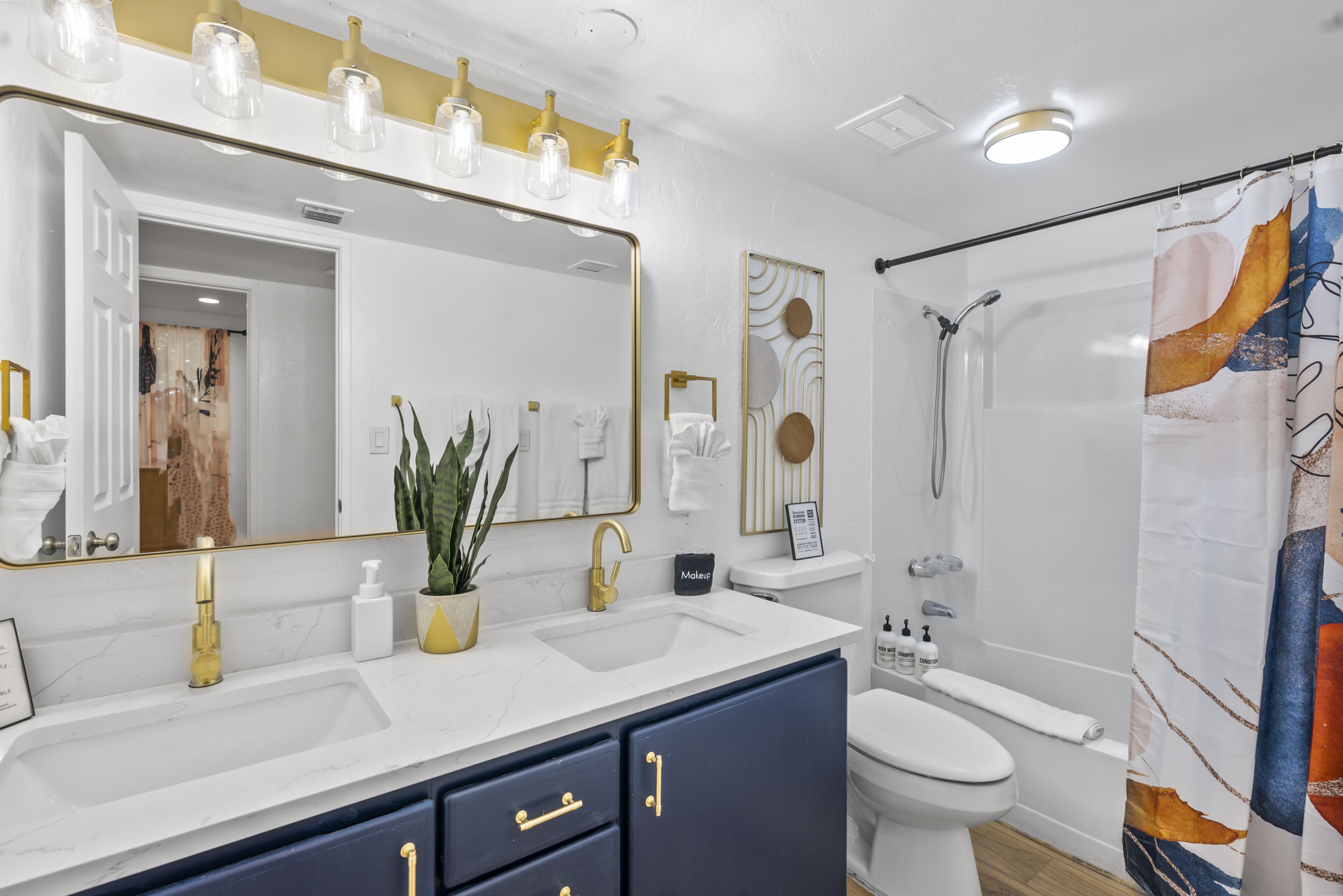 A modern bathroom with dual sinks, a large mirror, and a shower area.