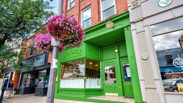 A storefront with a green facade and a hanging flower basket. - The Avonlea Inn (Stratford)