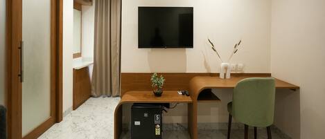 A modern room with a wooden desk, a green chair, a flat-screen TV, an air conditioner, and a small refrigerator.
