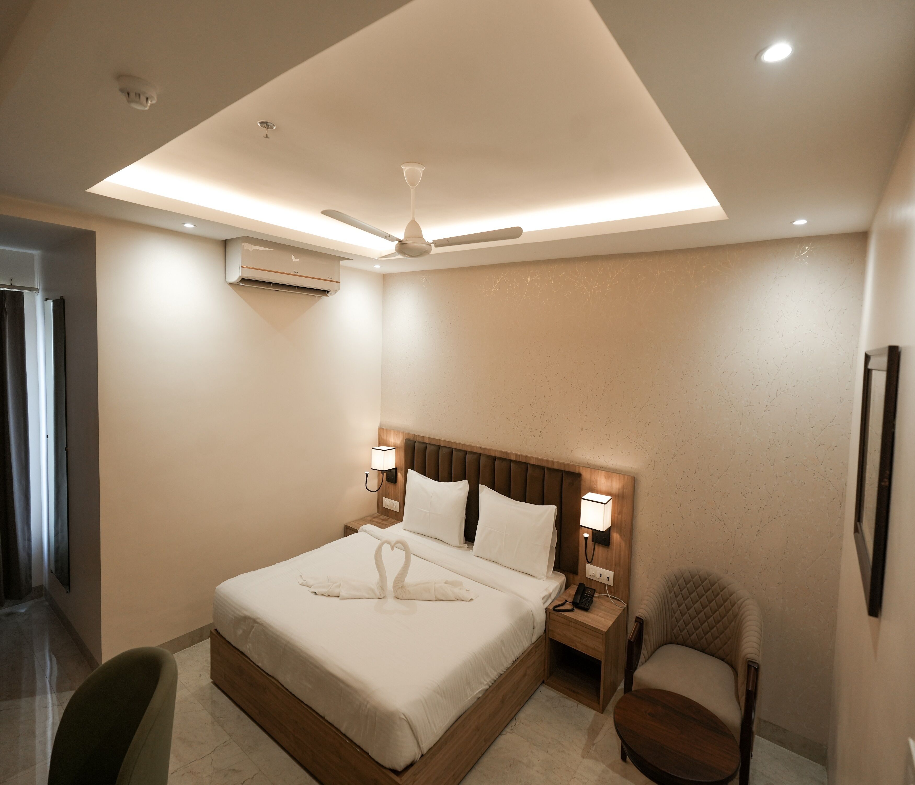 A hotel room with a bed, a chair, a nightstand, a lamp, and a ceiling fan.