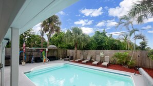 A swimming pool with lounge chairs and a wooden fence in the background. - Sunshine State of Mind House (Jensen Beach)