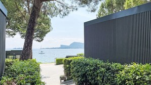 A pathway leading to a modern building with a view of the sea and mountains.